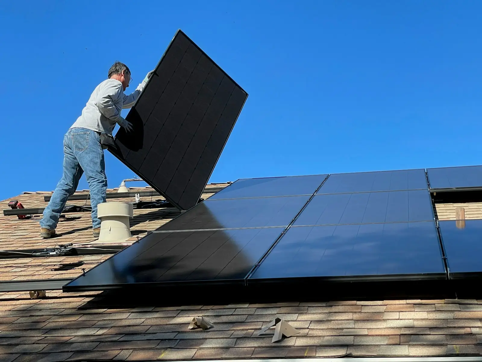 Instalador colocando un módulo solar sobre un techo residencial bajo cielo despejado