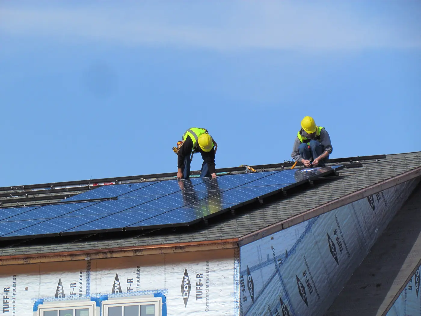 Dos instaladores con equipo de seguridad trabajando sobre un techo